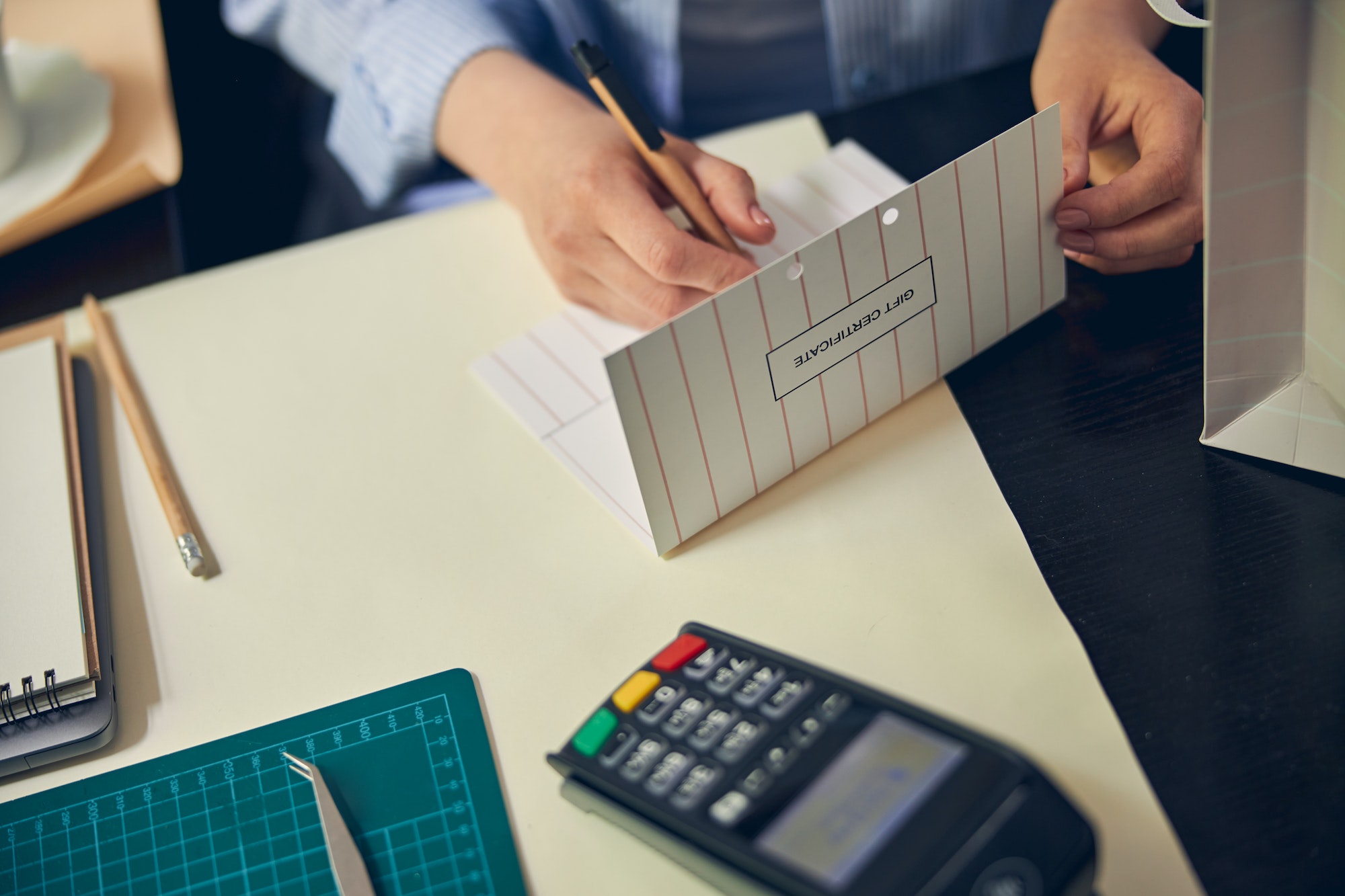 Hands of saleswoman writing on a gift card
